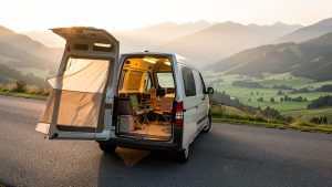 Van aménagé sur une route panoramique, portes arrière ouvertes, ambiance de voyage libre au milieu de la nature.