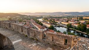 Vue panoramique de Château-Thierry depuis les remparts du château, avec la Marne en contrebas, les toits de la ville et les coteaux champenois au loin dans la lumière dorée de fin d’après-midi.